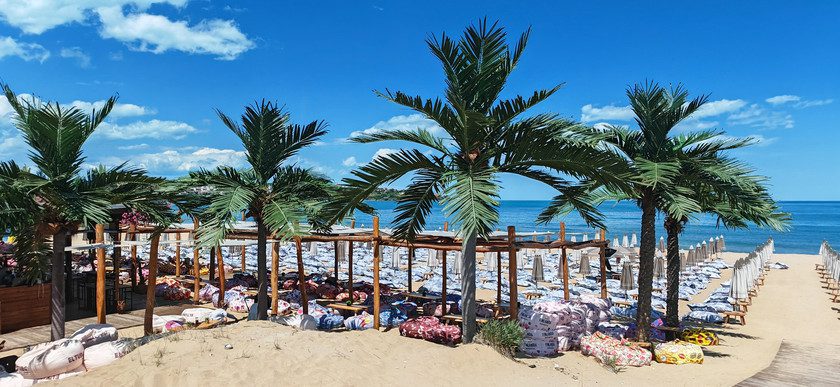 Плажът Каваци с палми, шезлонги и пуфове